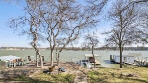 A lakeside patio with a covered seating area, a small shed, and a dock extending into the water. - The Lake Shack-----Water Front!!! (Brownwood)