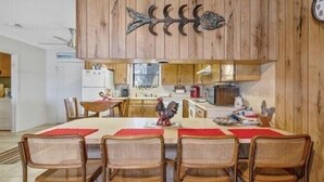 A dining area with a wooden wall, a fish decoration, and a clock. - The Lake Shack-----Water Front!!! (Brownwood)