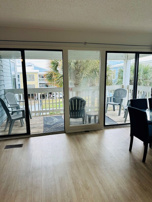 A spacious room with a large sliding glass door leading to an outdoor area with chairs and a table.