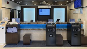 A reception area with a counter, a digital screen, and two self-service kiosks.