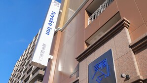 A hotel sign with foreign text and a building facade with a stone-textured wall and a balcony.