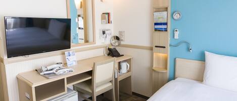 A hotel room with a bed, a desk with a computer, a television, a refrigerator, a microwave, a coffee maker, a hairdryer, a mirror, a clock, and a shower.