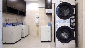 A laundry facility with two washing machines, a small refrigerator, and a water dispenser.