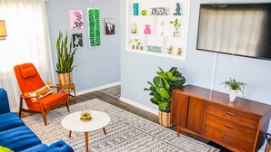 A living room with a blue sofa, an orange armchair, a white coffee table, and a wooden cabinet. - DEJA BLUE *Mid-Mod House *2Br/1Ba/1Ga* Near I27/I40* (Amarillo)