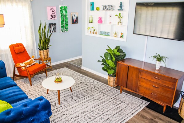 A living room with a blue sofa, an orange armchair, a white coffee table, and a wooden cabinet.