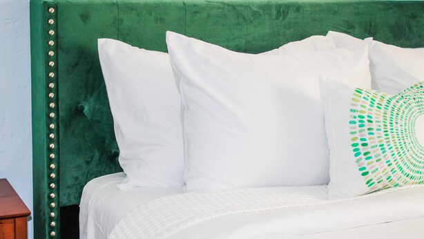 A bed with white bedding and a green upholstered headboard. - DEJA BLUE *Mid-Mod House *2Br/1Ba/1Ga* Near I27/I40* (Amarillo)