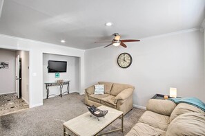 Un soggiorno con un divano color beige, un tavolino, una televisione e una ventola a soffitto.