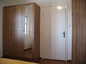 Features a spacious wardrobe with multiple drawers and a mirrored section, alongside a door with a black handle.