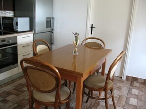 Compact kitchen with dining area, featuring a microwave, refrigerator, and oven, and a comfortable dining table with four chairs.
