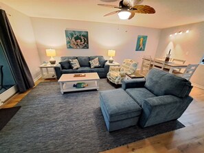 A living room with a sofa, armchair, coffee table, and a ceiling fan. - Seascape #1101 Newly Renovated Beach Service Included 2 Chairs and Umbrella (DESTIN)