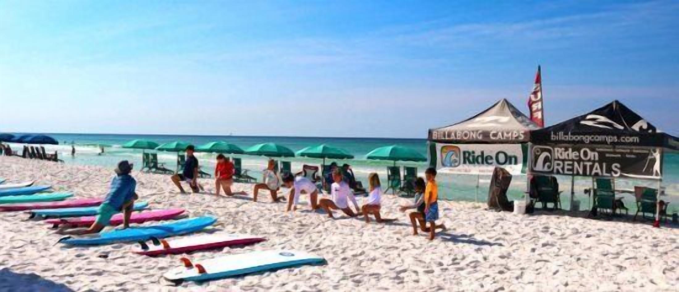 A beach with surfboards, tents, and a 'Ride On Rentals' sign.