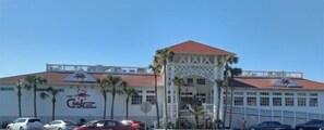 A building with a red roof, a white facade, and a sign that reads 'The Crab Shack.' There are palm trees in front of the building. - Seascape #1101 Newly Renovated Beach Service Included 2 Chairs and Umbrella (DESTIN)