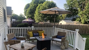 A deck with a fire pit, outdoor furniture, and a white fence.
