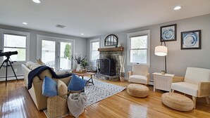 A spacious living room with a fireplace, a sofa set, a coffee table, and a lamp.