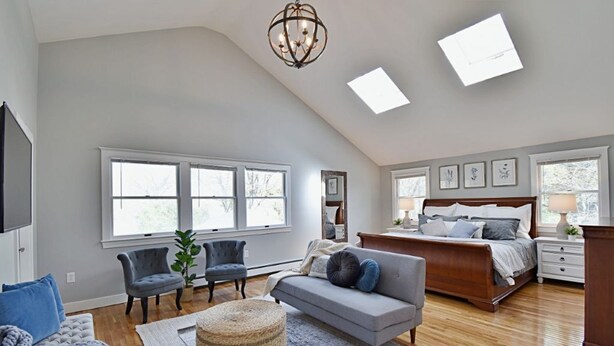 A spacious bedroom with a large bed, a sitting area with a sofa and chairs, and a television.