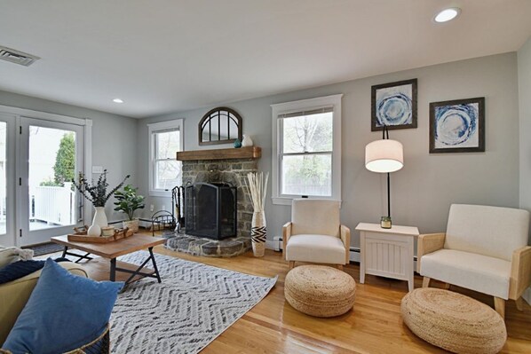 A spacious living room with a stone fireplace, a large window, and a comfortable seating area. - Spacious, Comfy Colonial, minutes to Boston and highways (Milton)