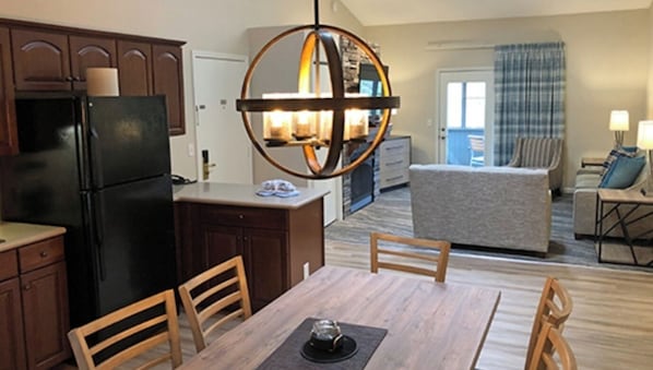 Cozy living space with a kitchenette, dining area, and seating area, featuring a wooden table, chairs, and a sofa.