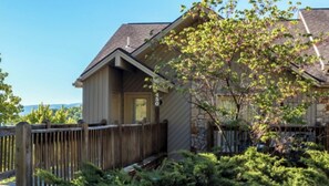 Stunning two-story home with a gabled roof and inviting front porch, surrounded by a beautifully maintained garden and a wooden fence.