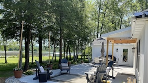 Een terras met buitenmeubilair, een pergola en uitzicht op een meer.