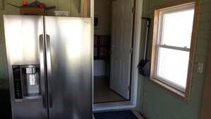 Una cocina compacta con un refrigerador de acero inoxidable, una cafetera integrada y una ventana pequeña.