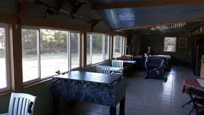 Habitación con mesa de futbolín, equipo de ejercicio y amplias ventanas con vistas al exterior.
