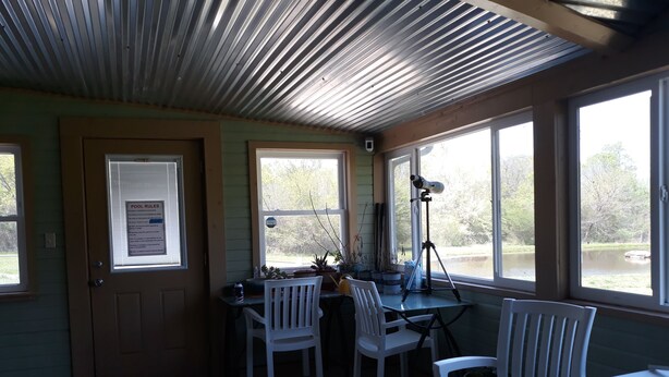 Una habitación con escritorio, sillas, un telescopio y ventanas con vistas al agua.