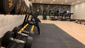 A gym with weightlifting equipment, treadmills, and exercise machines. - Tripper Inn (Dammam)