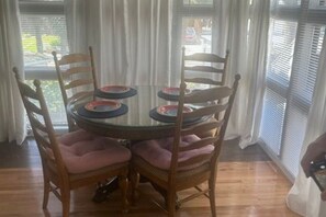 Una mesa redonda de cristal con cuatro sillas, cada una con un asiento acolchado.