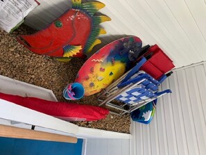 Ein Lagerraum mit verschiedenen Gegenständen, darunter ein roter, fischförmiger Gegenstand, ein blau-gelbes Objekt und ein rot-blauer Stuhl.