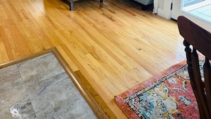 A living room with hardwood flooring, a patterned armchair, a sofa, a small table with a lamp, and a ceiling fan. -  Elevated Apt steps from beach. Furnished Parking Utilities, TV Internet Include (Tybee Island)
