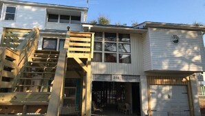 Un edificio de dos pisos con un porche delantero, una escalera y un garaje.