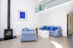 A modern living room with a fireplace, striped sofas, a white coffee table, and a staircase.