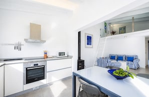 A modern kitchen with a microwave, oven, and a stove. There is a dining area with a table and chairs.