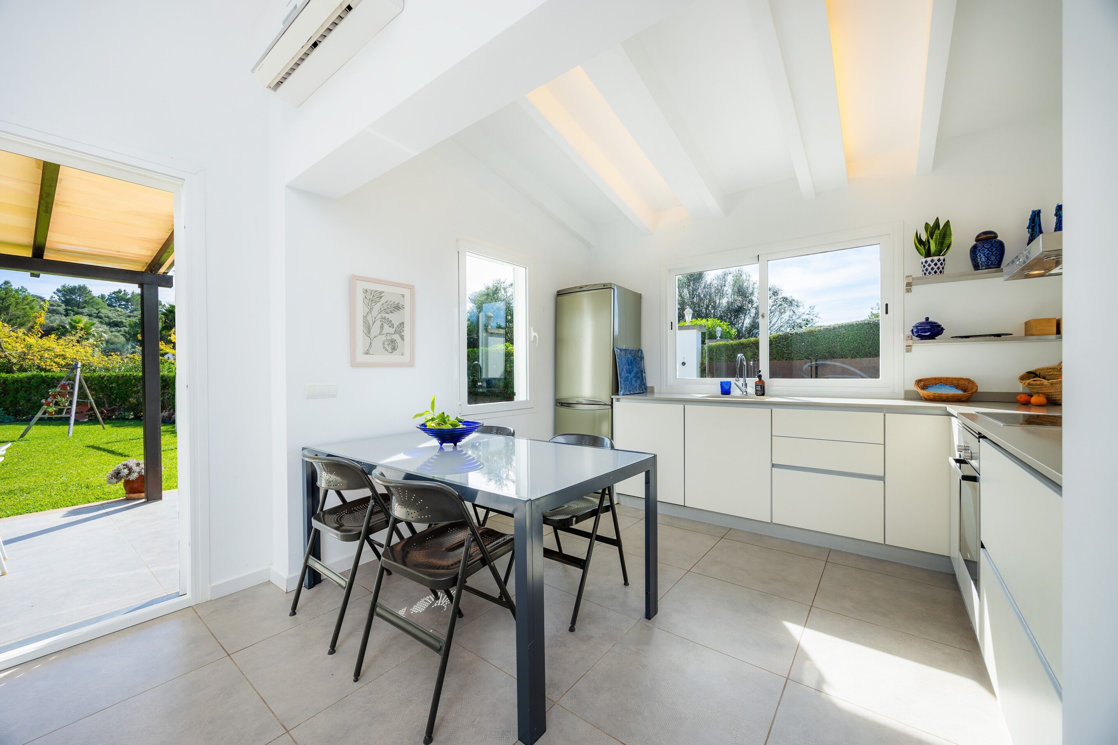 Une cuisine moderne avec un coin repas, de grandes fenêtres et une vue sur le jardin.