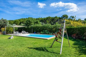 A swimming pool with lounge chairs, a shaded area, and a wooden ladder.