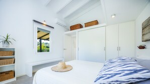 Ein Schlafzimmer mit Bett, Fenster, Kleiderschrank und einem Regal mit Körben.