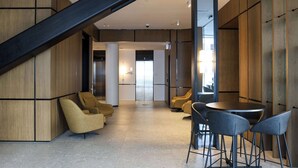 A modern lobby with a staircase, seating area, and a round table. - Wyndham Garden Christchurch (Christchurch)