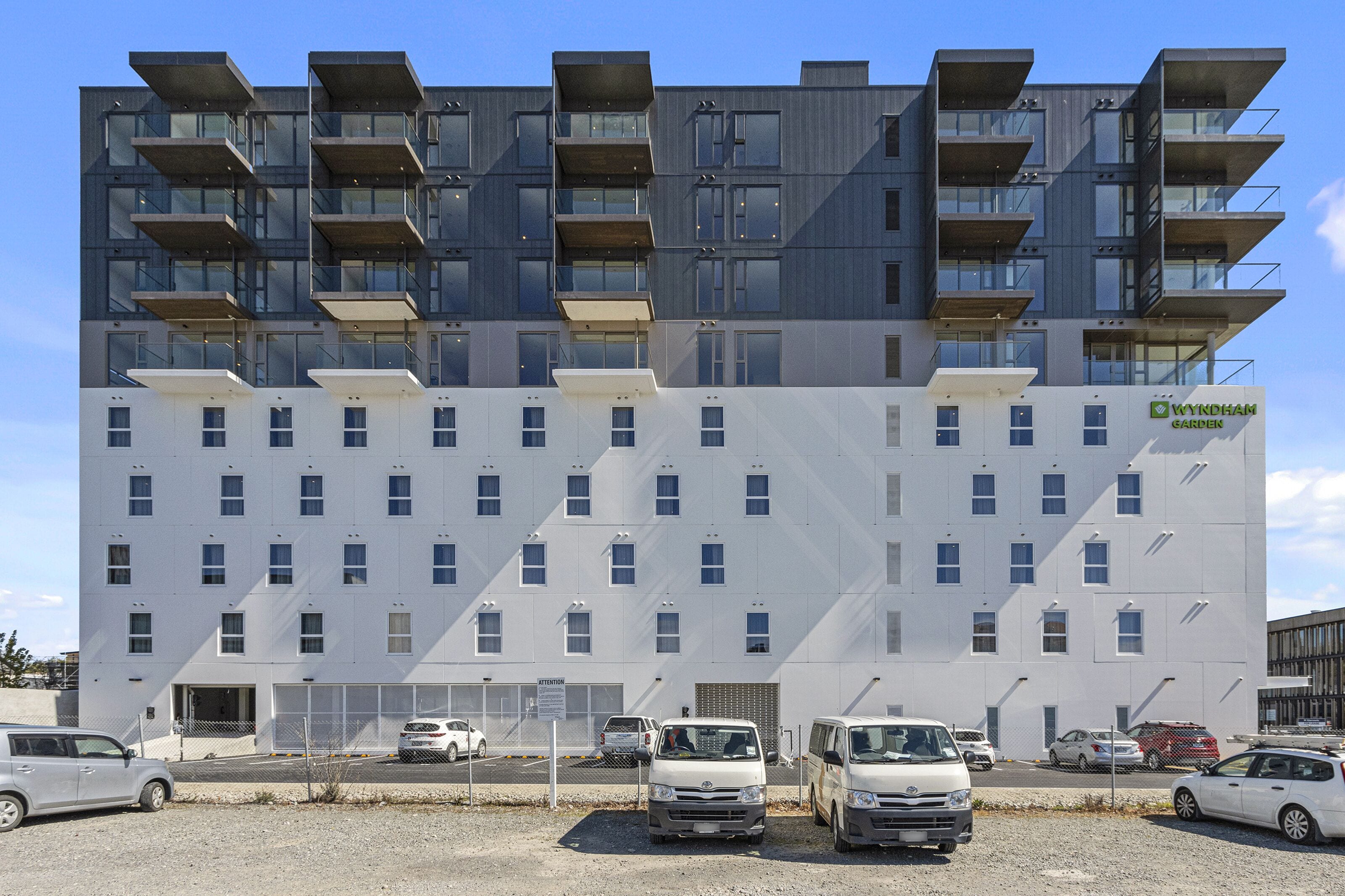 A modern multi-story building with a white facade and multiple balconies.