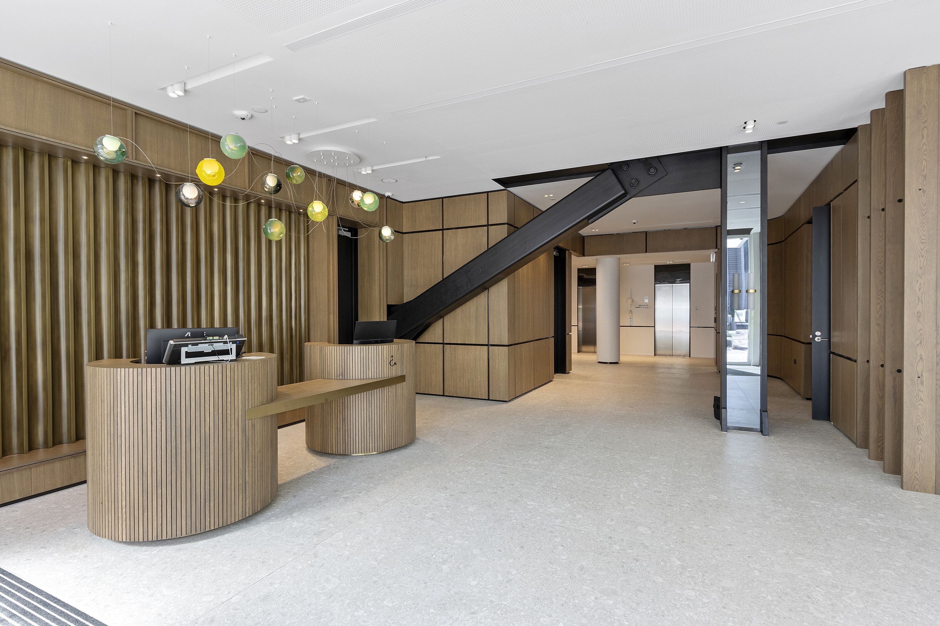Un área de recepción moderna con un mostrador de madera, una escalera y vistas al interior.