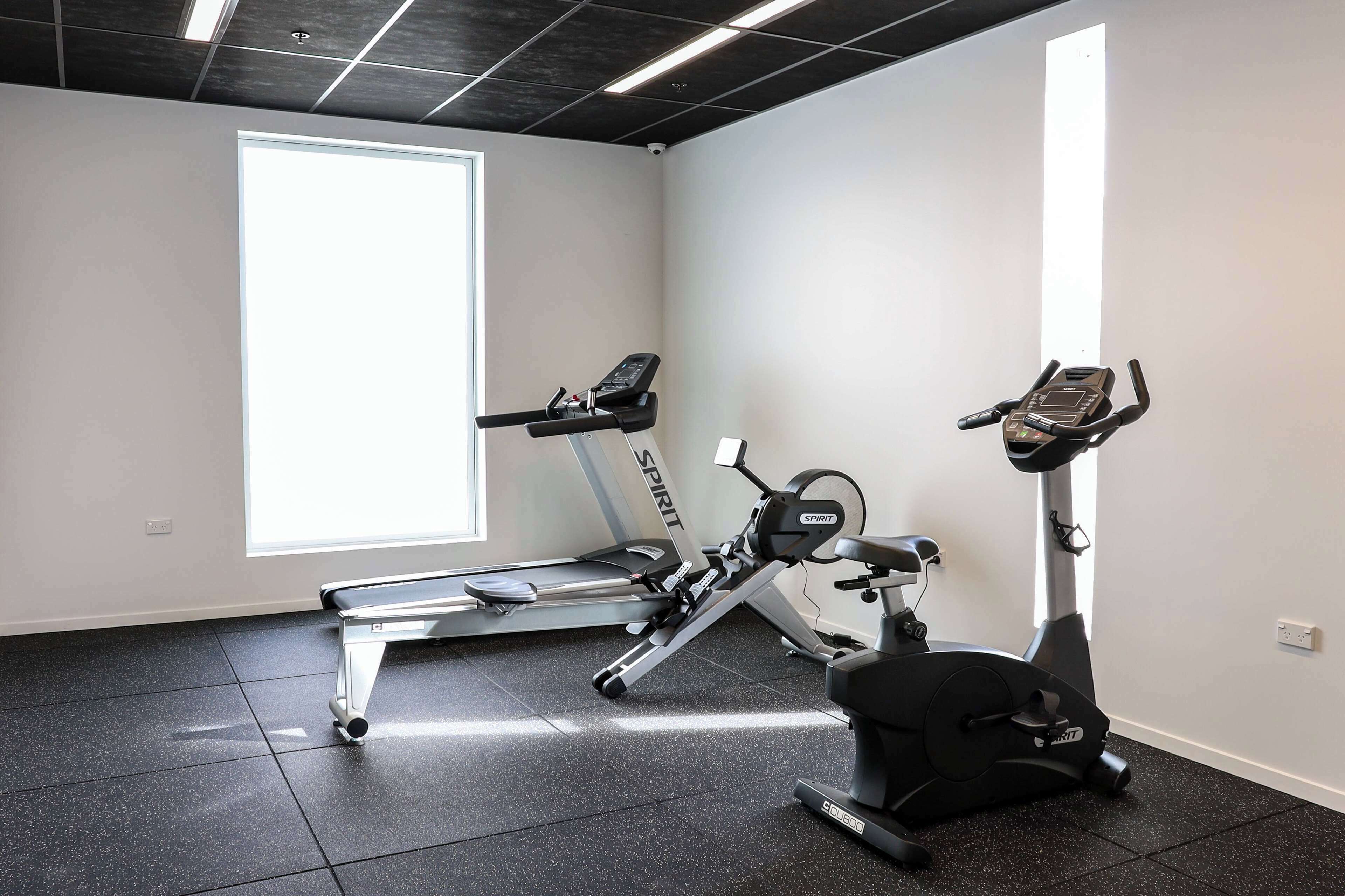 Une salle de sport équipée d’un tapis de course, d’un vélo elliptique et d’un vélo d’appartement.