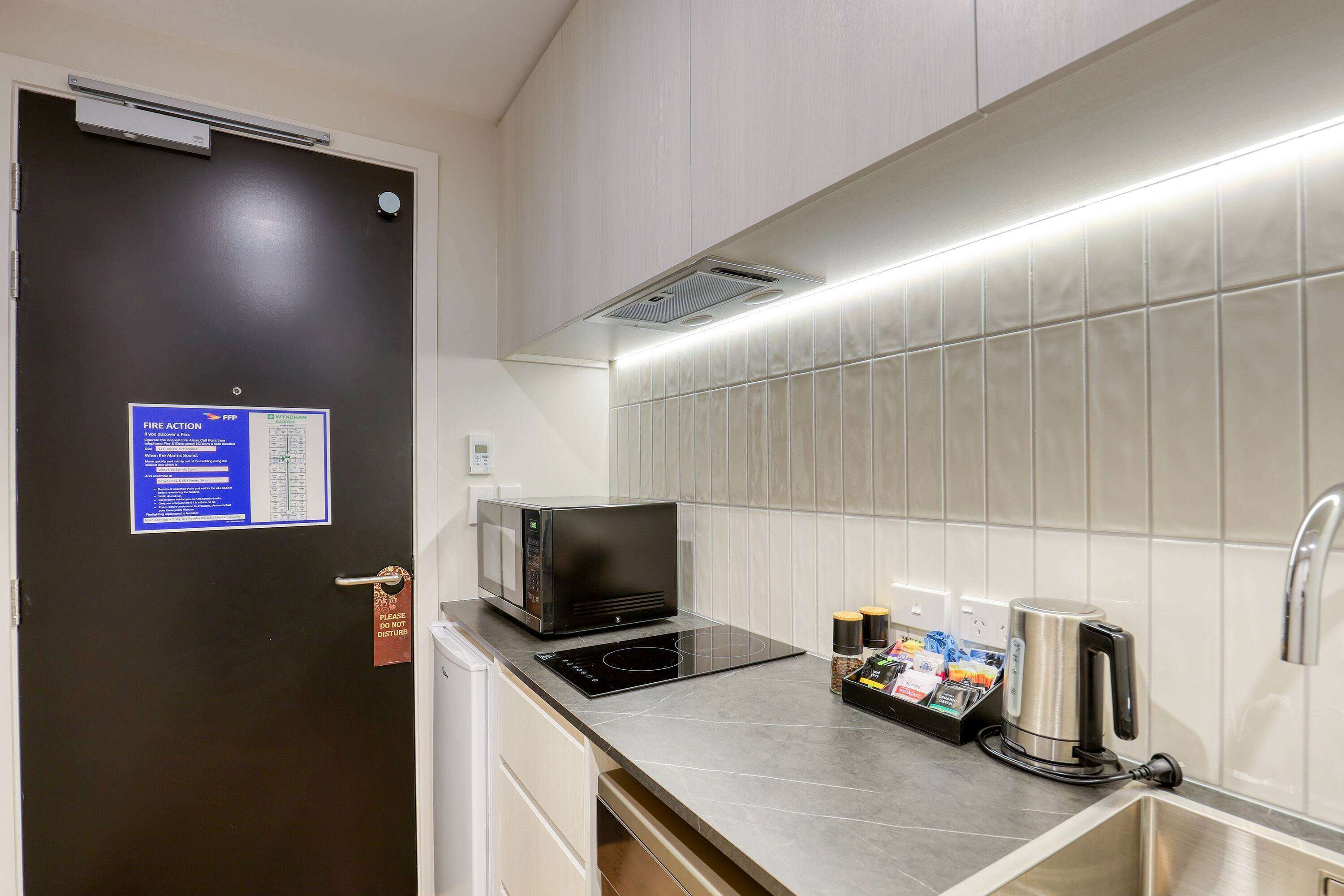 A modern kitchen with a microwave, kettle, and a coffee maker on the counter.