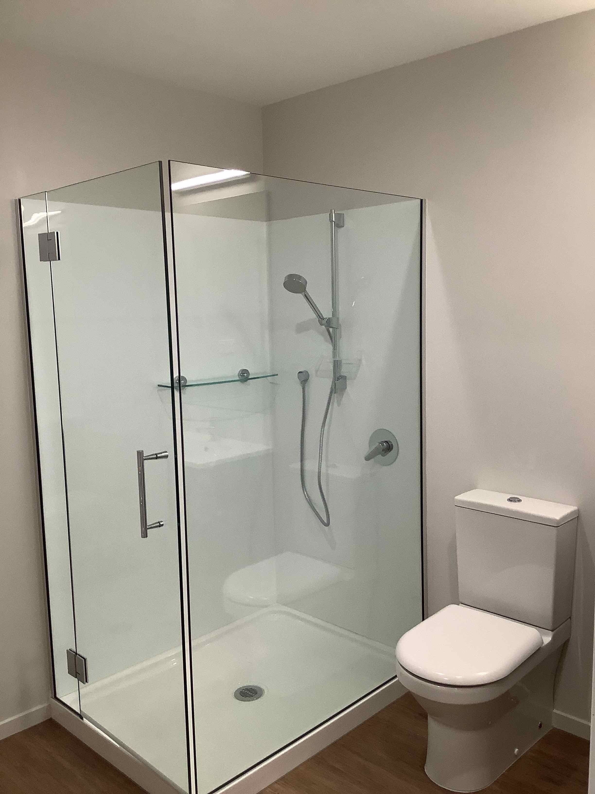 Een douche met glazen wand en een toilet aan de rechterkant.