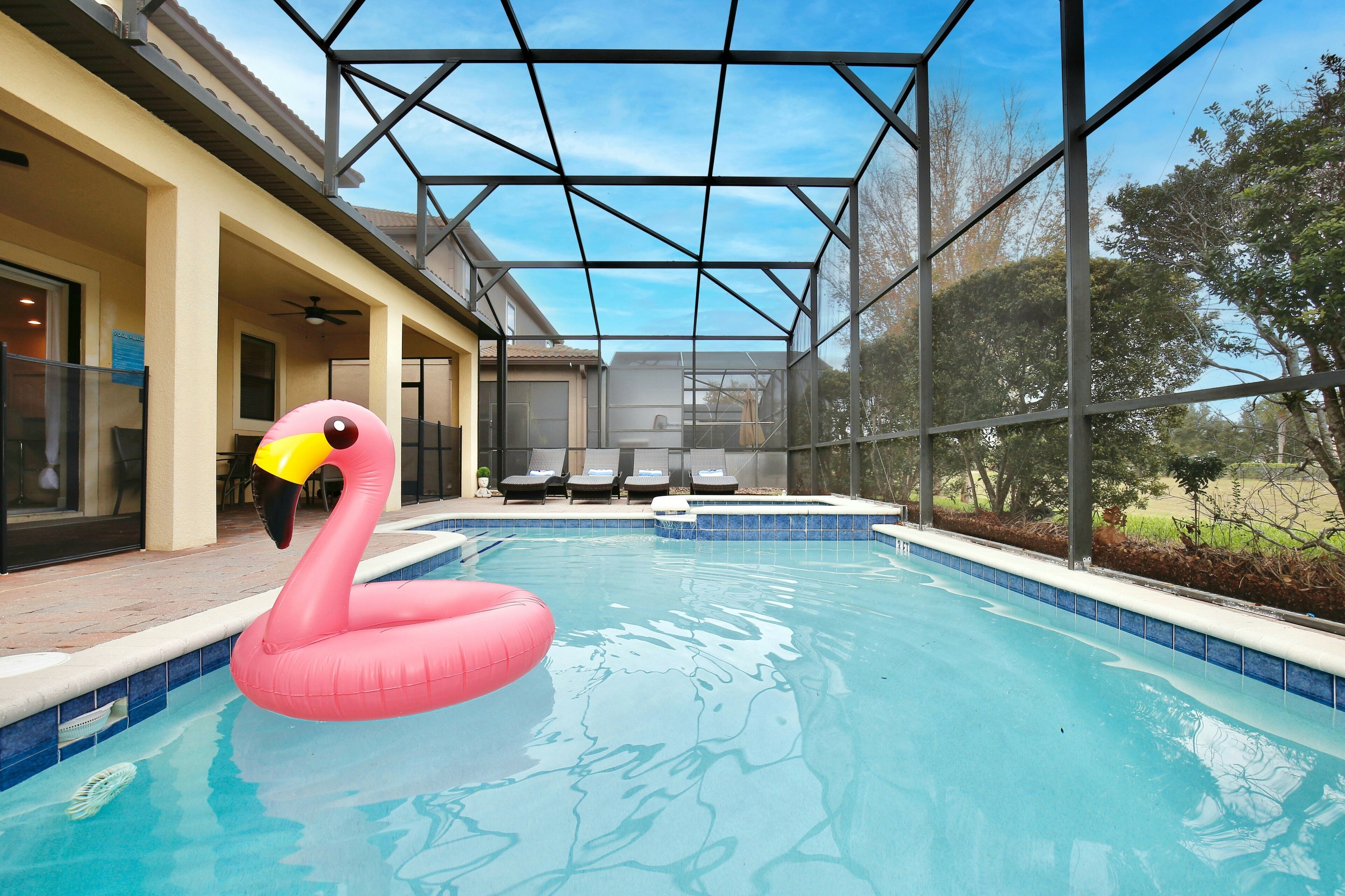 Une piscine agrémentée d’un flotteur en forme de flamant rose, un patio couvert et une vue sur le paysage environnant.