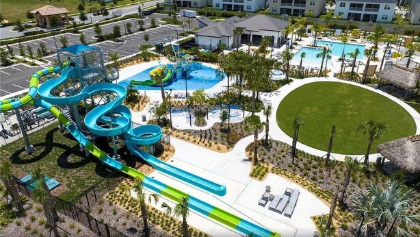 A water park with multiple slides and pools, surrounded by a well-maintained lawn and palm trees. - Family vacation w/ Private Pool/Spa close to Disney,Parks & Golf (Champions gate)