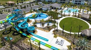Um parque aquático com vários toboáguas e piscinas, rodeado por um gramado bem cuidado e palmeiras.