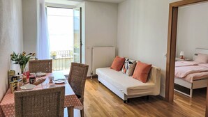 Un espace de vie compact comprenant un coin repas, un canapé et un lit.