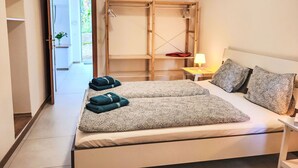 Une chambre à coucher avec un lit, une table de chevet avec une lampe, une armoire et une vue sur l’extérieur.