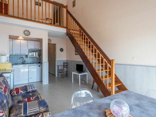 Spacious living area with a kitchen, dining space, and staircase leading to an upper level.