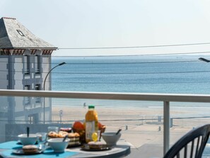 Enjoy a seaside breakfast on this balcony with a view of the ocean and a ship in the distance.