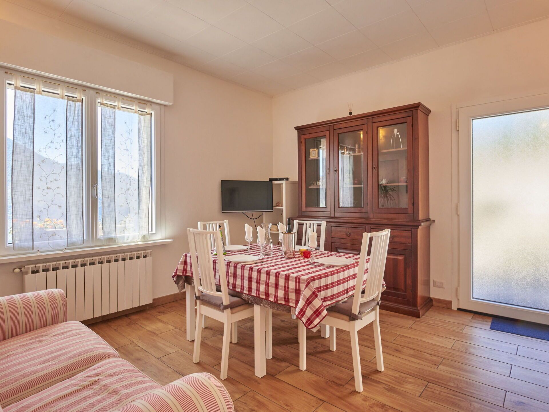 Un coin repas avec une table dressée pour quatre personnes, flanqué d’un buffet et d’un t éléviseur.